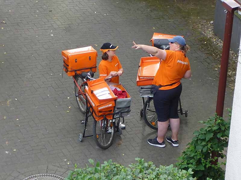 2 Postbotinnen mit Rädern machen Pause