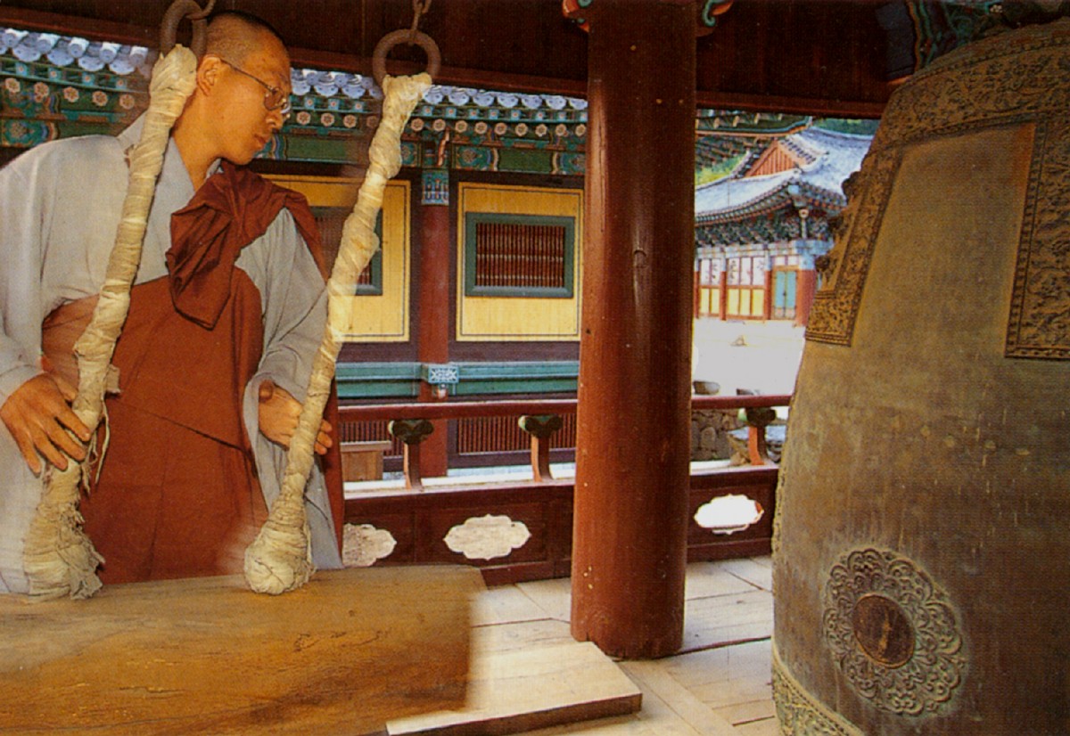 Gebet und Glockenklang, ein Mönch schlägt mit einem schweren Balken die mächtige Glocke im Songgwangsa-Kloster in Südkorea an